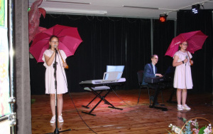 Dzień Dziecka w PMDK - dwie dziewczynki z różowymi parasolkami śpiewają piosenkę.
